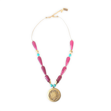 Collar corto con una espectaculares lágrimas de ágatas facetadas burdeos, howlite turquesa y zamak con baño de oro mate. Este collar tiene una preciosa pieza central de un medallón con flor que seguro conseguirán resaltar tu look favorito.